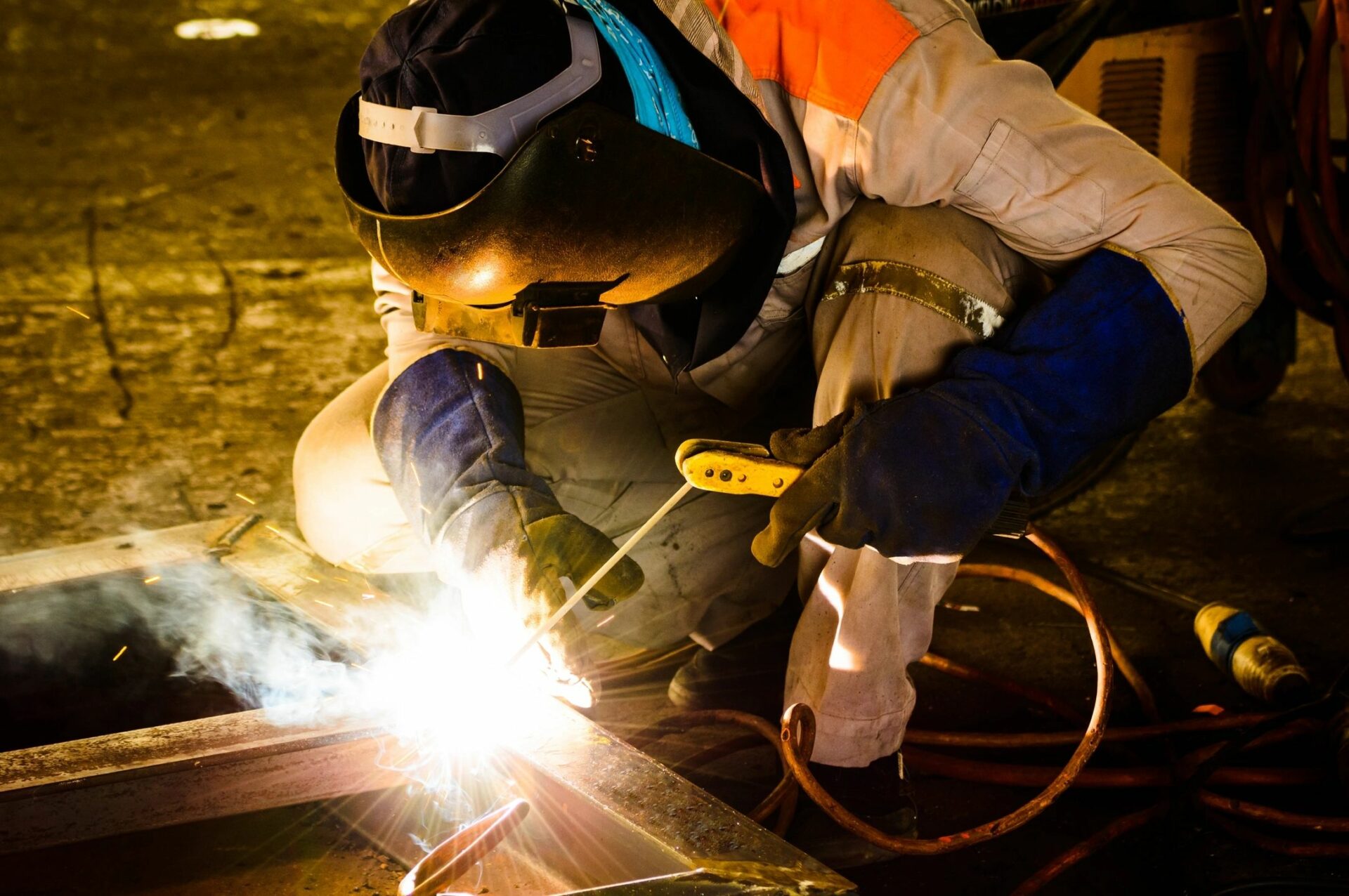 Man welding and creating sparks while wearing a welder mask.